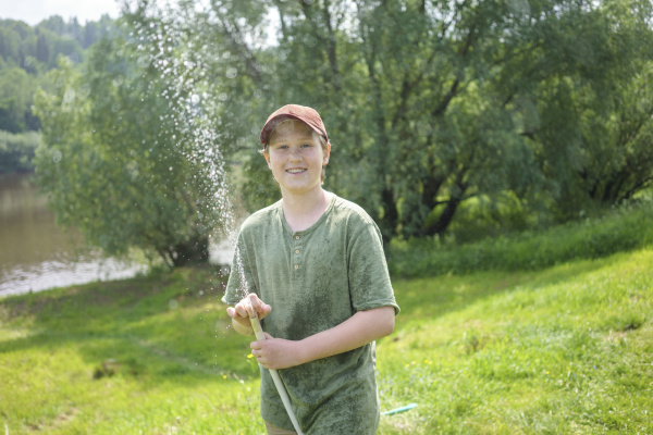 smiling boy holding hose while standing