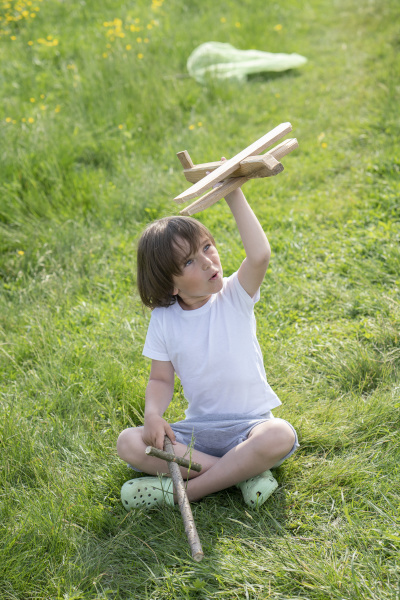 playful boy flying model airplane while