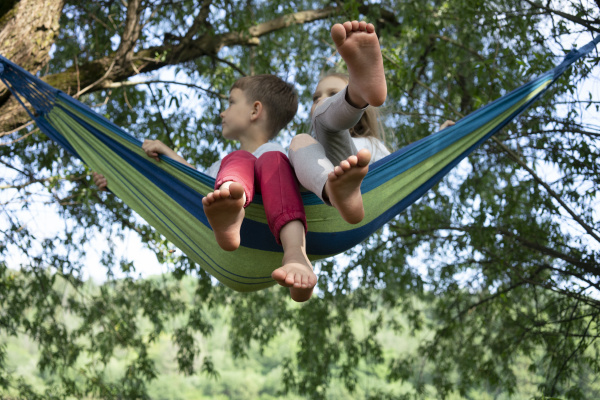 children relaxing on hammock against trees