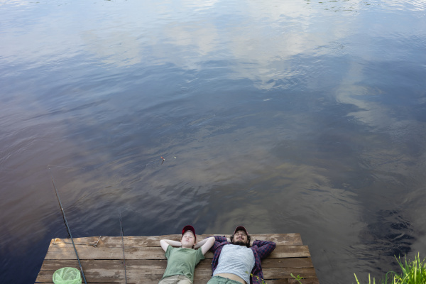 father and son lying on boardwalk