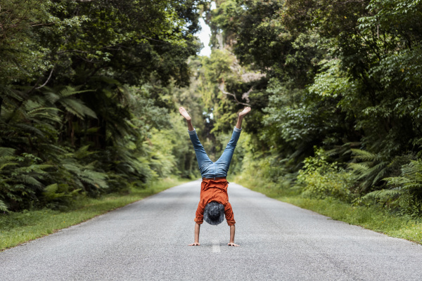young man performing handstand on road