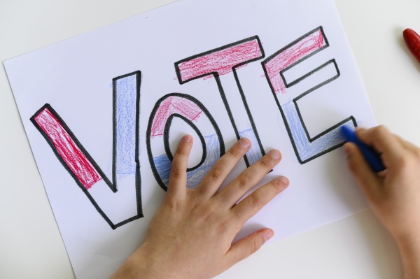 child s hands coloring vote sign
