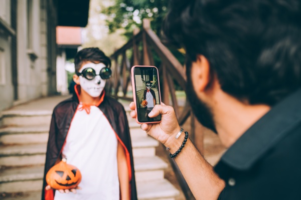 father photographing son in halloween costume