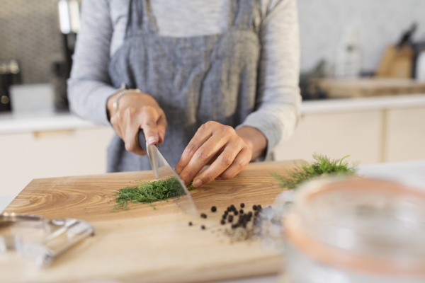 woman slicing fresh herbs on cutting