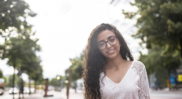 young woman wearing eyeglasses standing against