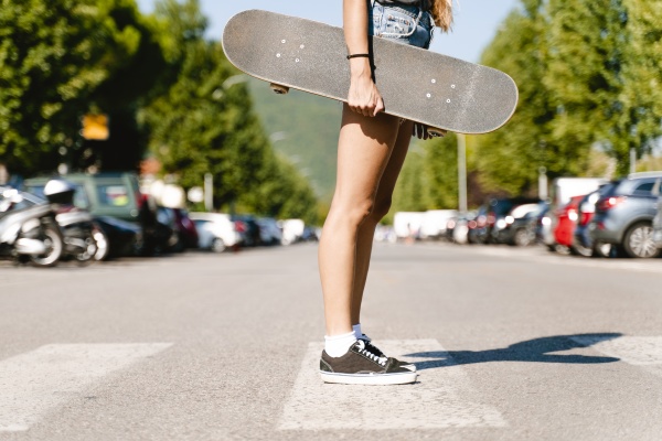 woman holding skateboard while standing on
