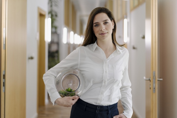 businesswoman holding terrarium while standing at