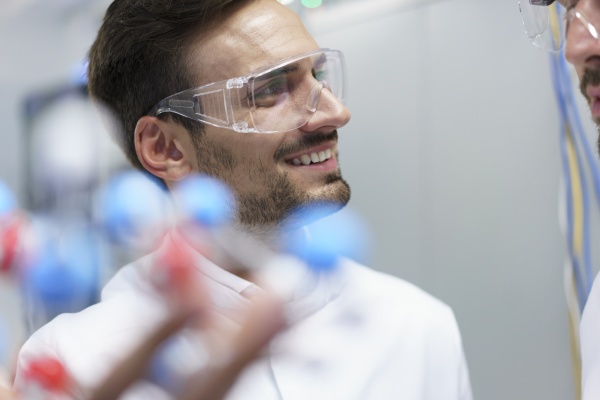 smiling male scientist holding molecular structure