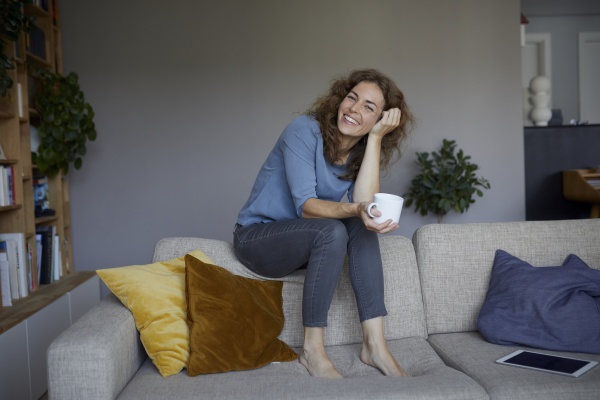 smiling woman drinking coffee while sitting
