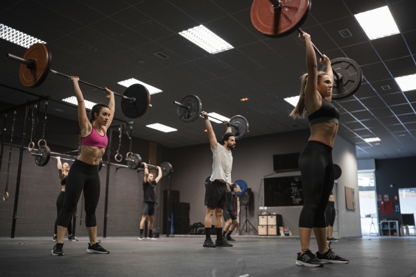 athletes lifting barbell while exercising in