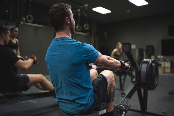 man using rowing machine with people