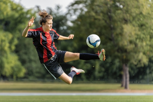 young woman playing soccer in field