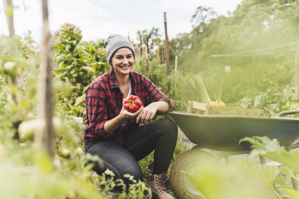 smiling woman holding red bell pepper