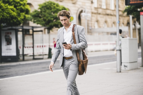 businessman using mobile phone while walking