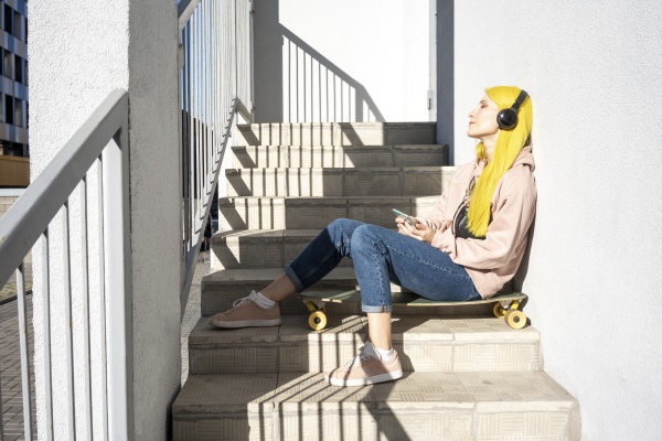 young woman listening music through headphone