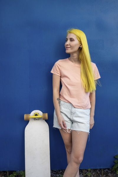 young woman with skateboard standing against