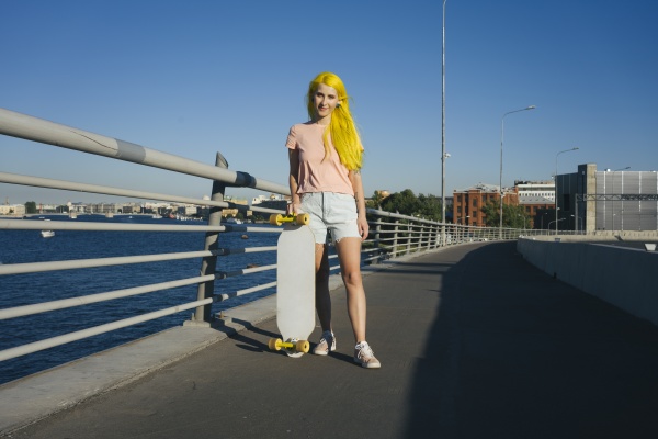 young woman standing with skateboard on