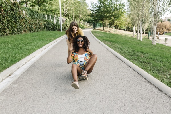 young woman pushing her friend sitting