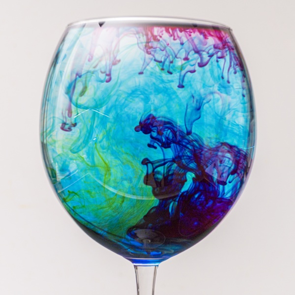 colorful ink drips into glass with