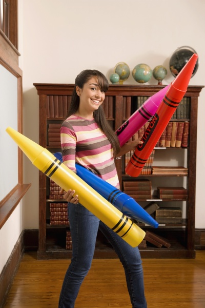 teenage girl holding oversized crayons and