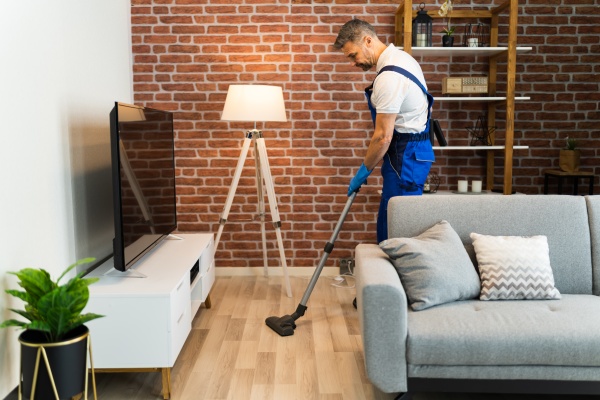 man in uniform vacuuming house floor