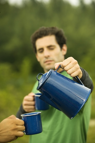 mid adult man pouring coffee into
