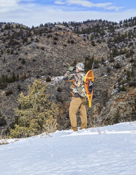 hunter with snowshoes and rifle standing