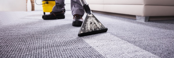 person cleaning carpet with vacuum cleaner