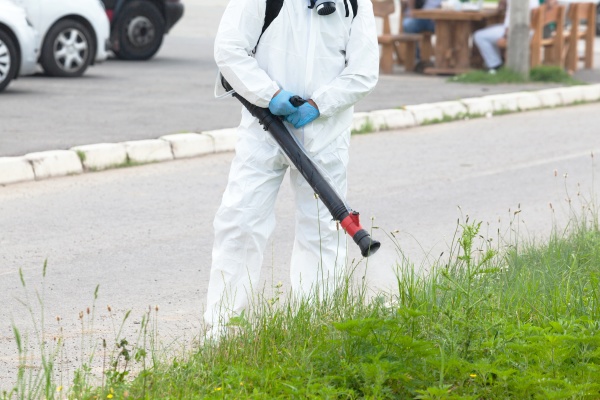 worker in protective suit spray disinfectant
