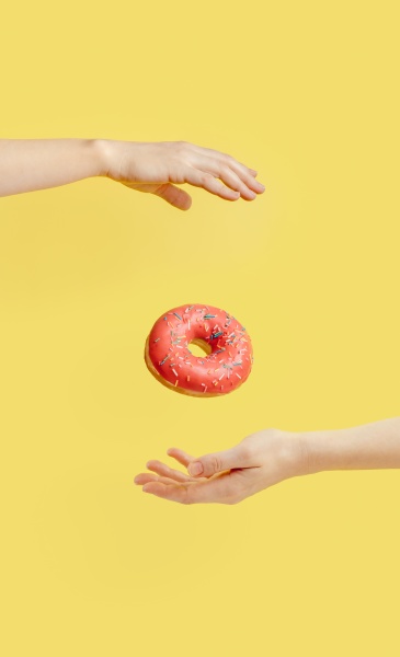 donut falls between hands on yellow