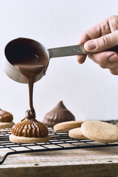 pouring chocolate cream on cookies with