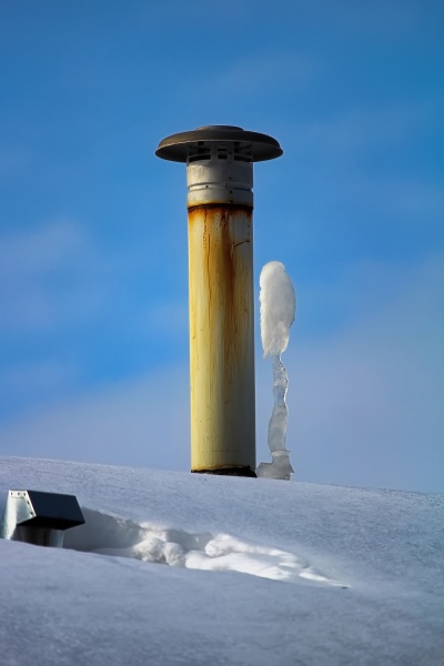 frozen icicles beside a chimney stack