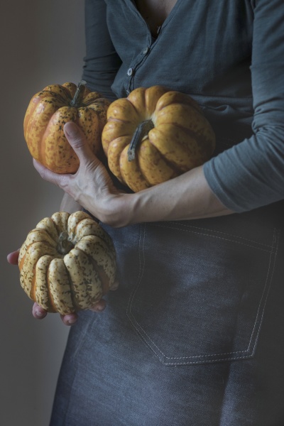 woman holding three tiny pumpkins while