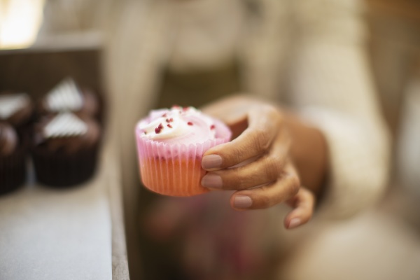 close up female baker holding cupcake