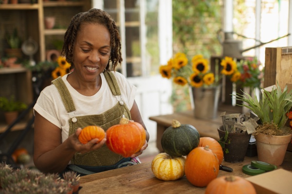 female florist arranging autumn pumpkins in