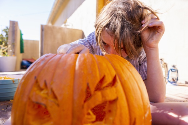 young boy carving pumpkin on patio