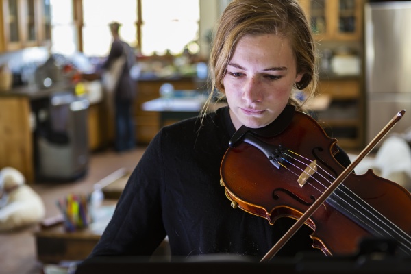 teenage girl practicing violin at home