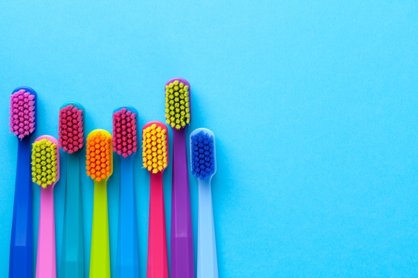 colorful toothbrushes over blue paper background