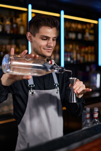 bartender in apron adds ingredient to