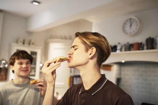 hungry teenage boys eating pizza in