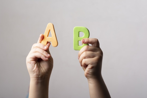 hands holding two spongy alphabet ab