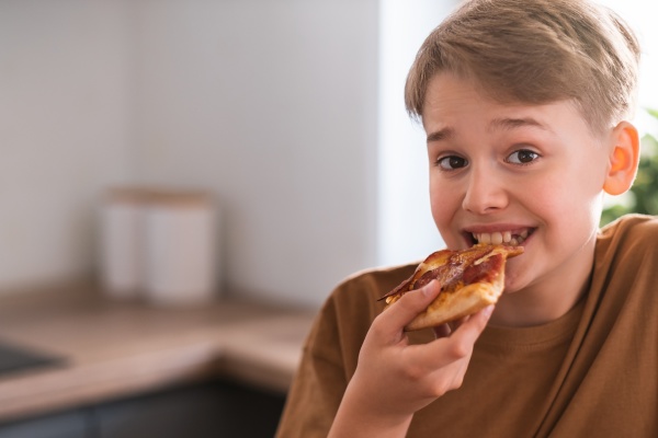 happy teenager enjoying eating delicious pizza