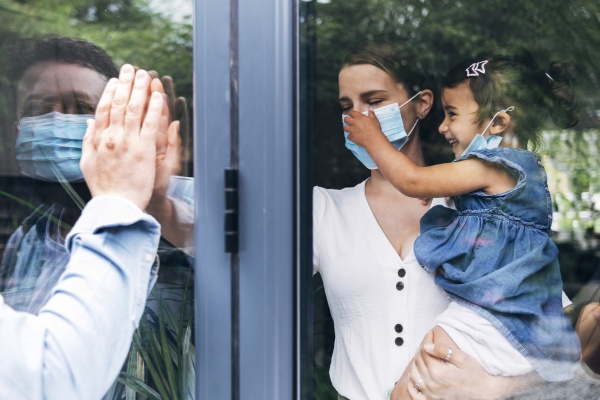 man greeting family through glass door