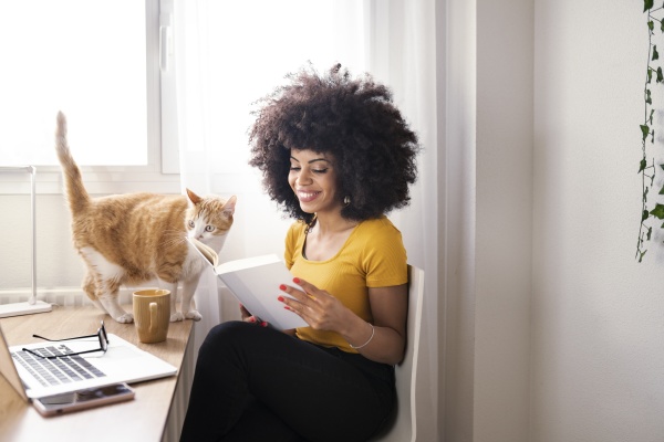 young businesswoman reading book while cat