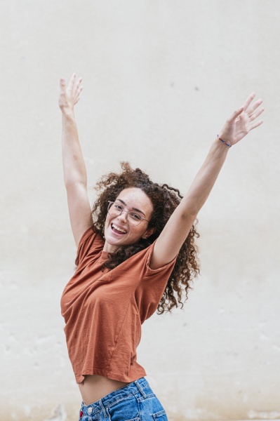 cheerful young woman dancing with arms