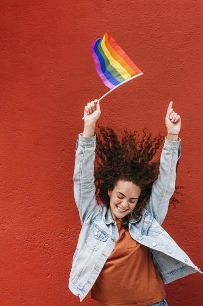 happy young woman holding rainbow flag