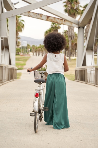 afro woman with bicycle walking on