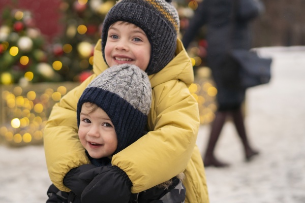 smiling brothers embracing at christmas market