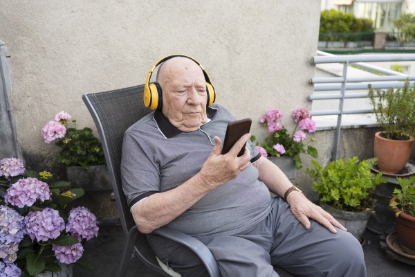 senior man holding smart phone listening