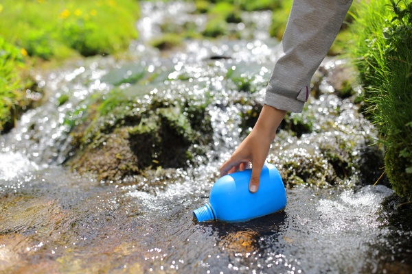 Hiker hand filling canteen with river water - Royalty free image ...